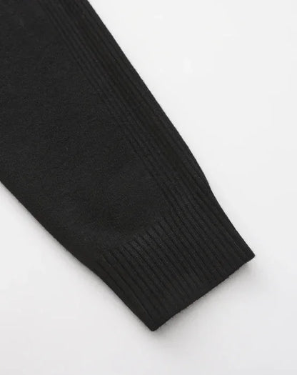 Close-up of black ribbed sweater sleeve on white background