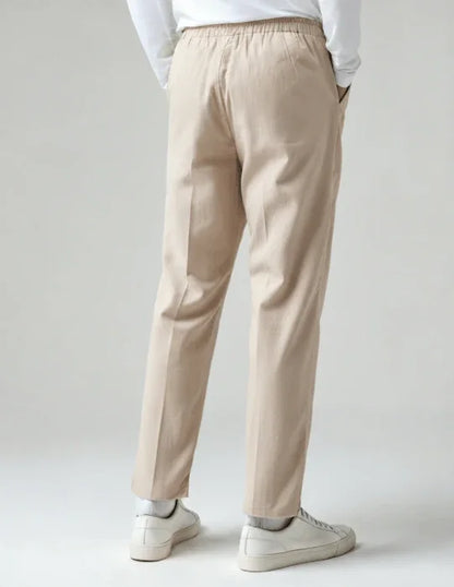 Back view of beige casual pants with elastic waistband, white sneakers, and white top