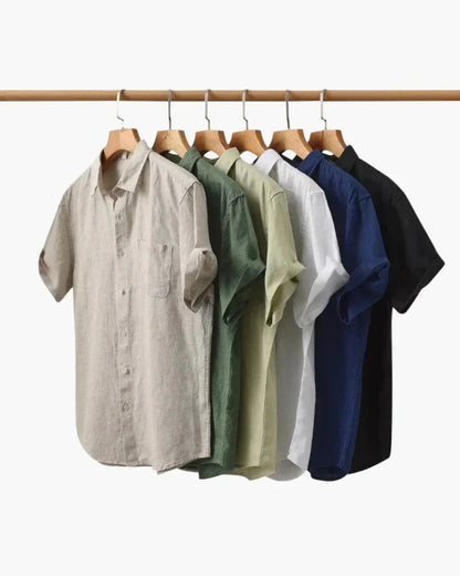 Linen short sleeve shirts in beige, green, olive, white, blue, and black on wooden hangers