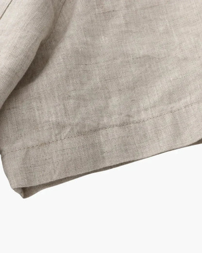 Beige linen t-shirt fabric close-up with visible texture and stitched hem