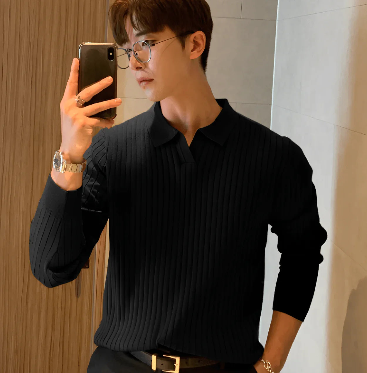 Man wearing black ribbed knit sweater with collar taking selfie in modern indoor setting
